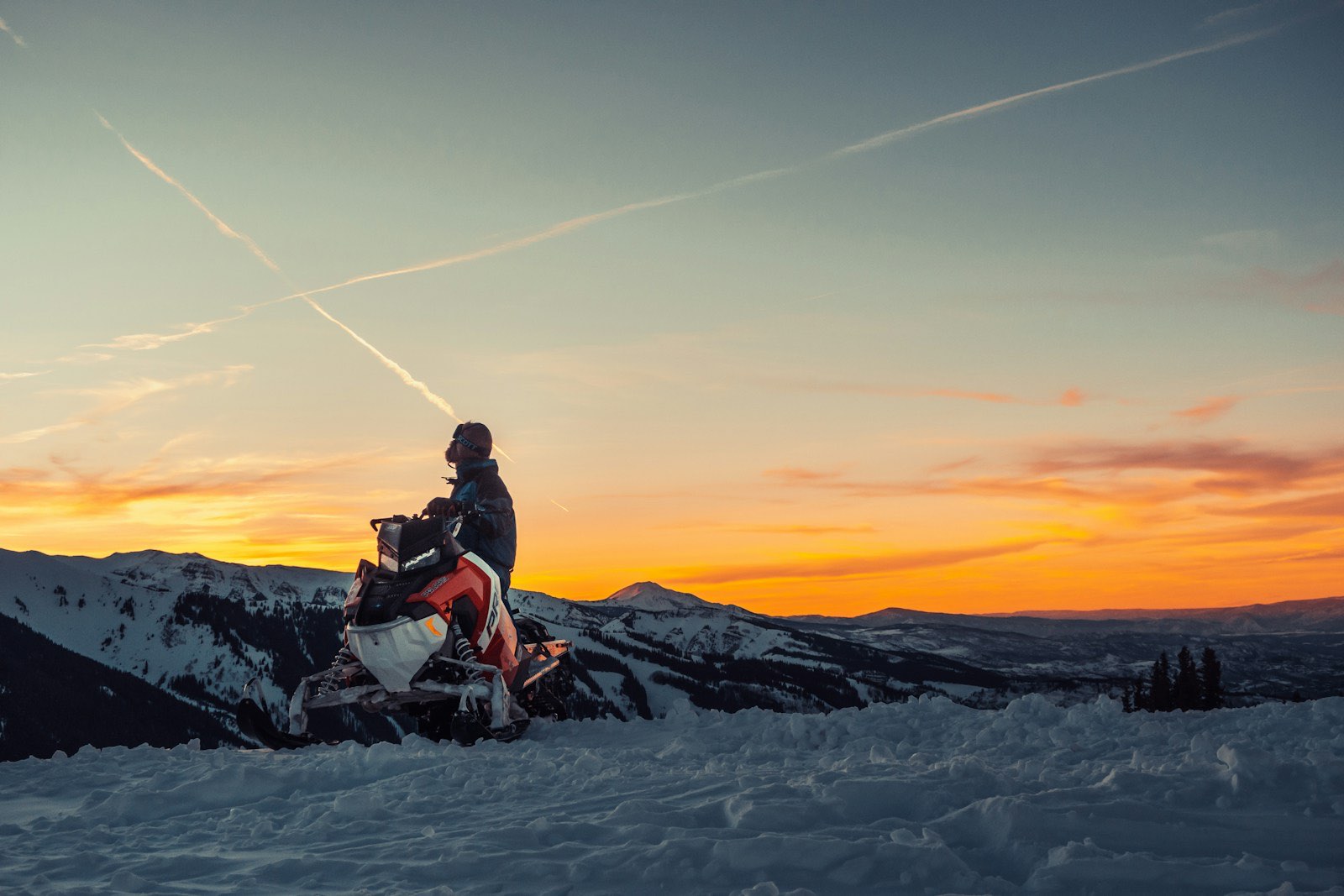 Snowmobiler at a mountain lookout at sunset