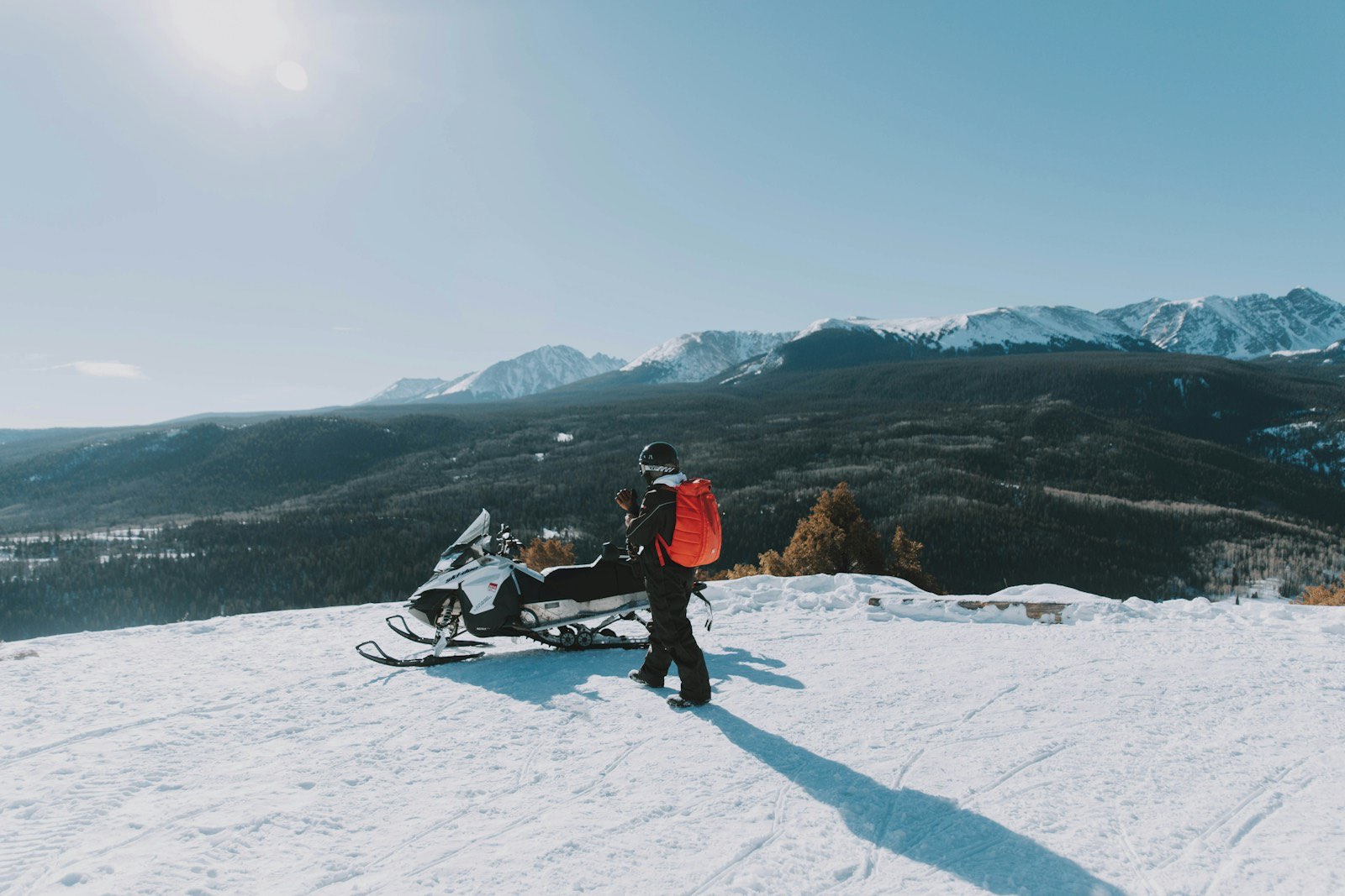 Rider stopped at a ridge viewpoint over forested valleys and peaks